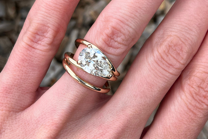 Close-up of a hand wearing two rings with a clear gemstone.